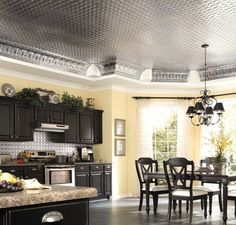 a dining room and kitchen area with black cabinets, granite counter tops and an ornate ceiling