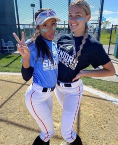 two softball players pose for a photo on the field