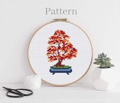 a cross stitch pattern with a bonsai tree in the center and some scissors next to it