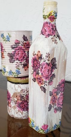 two vases with flowers painted on them sitting on a table next to each other