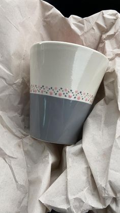 a white and blue cup sitting on top of a pile of paper covered in tissue