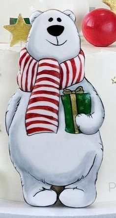 a cake decorated with a polar bear holding a christmas present and wearing a striped scarf