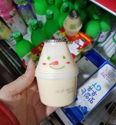 a person holding up a milk bottle in front of a shelf