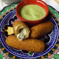 some food is on a colorful plate with a bowl of dipping sauce in the middle