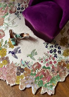 a pair of shoes sitting on top of a rug next to a purple velvet chair