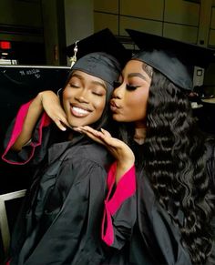 two women in graduation gowns hugging each other