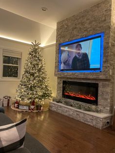 a living room with a christmas tree and a tv on the wall in front of it