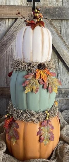 three stacked pumpkins with fall leaves on them