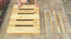 a little boy that is standing on top of a wooden pallet with flowers in the background