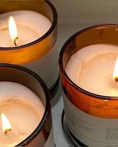 three white candles are sitting in tins