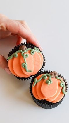 two cupcakes with frosting decorated like pumpkins