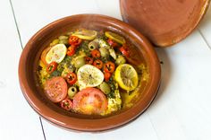 a brown bowl filled with lots of different types of food on top of a white table