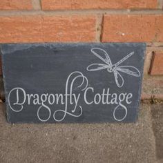 a slate sign that says dragonfly cottage with a dragonfly on it's back