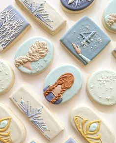 many decorated cookies are arranged on a white table top with blue and yellow frosting