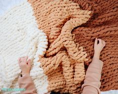 a woman is laying on the floor next to a pile of knitted blankets