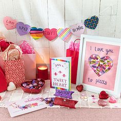 valentine's day greetings and cards are displayed on a table with candles, hearts, and other items