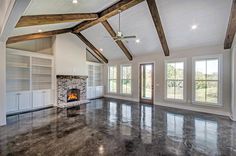 an empty living room with fireplace and large windows