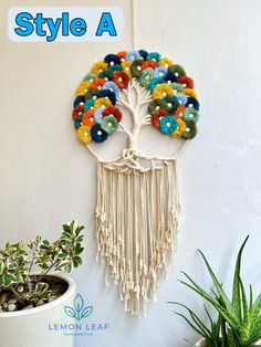 a wall hanging with a tree made out of yarn and beads on it's side