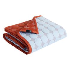 an orange and white polka dot blanket folded on top of each other in front of a white background