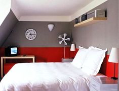 a white bed sitting in a bedroom next to a red and gray wall with a clock on it