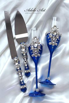 three blue wine glasses with crystal decorations on them and a silver knife next to it