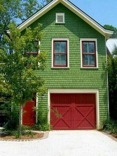 a green house with two red garage doors