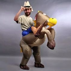 a man in an inflatable costume is holding onto a large stuffed animal that looks like a horse