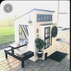 a small white house sitting on top of a brick floor next to a green field