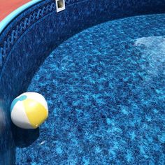 an inflatable beach ball sitting on the edge of a pool with blue water