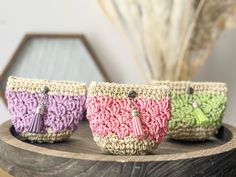 three small crocheted purses sitting on top of a wooden table next to a mirror