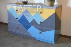 a dresser with mountains painted on it and a potted plant sitting on top of it