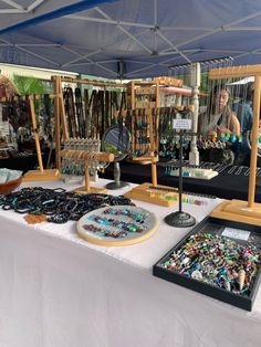 a table with many items on it and a woman in the background looking at them