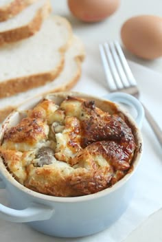 bread and eggs are on the table next to a casserole in a blue dish