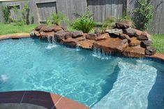 a pool with rocks and water features a waterfall