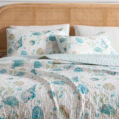 a bed with blue and green floral bedspread, pillows and pillowcases