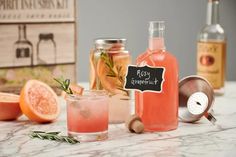 two bottles of pink grapefruit, one with rosemary and the other with an empty bottle