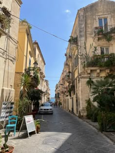 an empty street with cars parked on both sides and potted plants in the middle