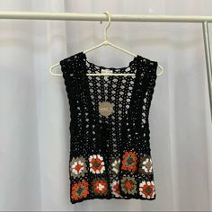 a black crocheted top hanging on a white hanger next to a curtain