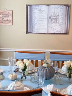 the table is set with white flowers and pumpkins