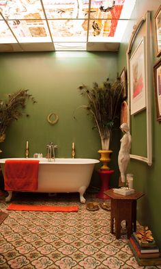 a bath tub sitting under a skylight next to two vases filled with plants