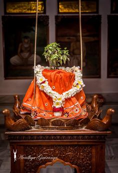 an orange and white dress with flowers on it is hanging from a wooden stand in the middle of a room