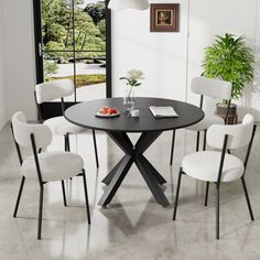 a black table with white chairs and a potted plant in the corner next to it