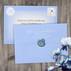 a blue envelope with a wax stamp on it and some flowers in the corner next to it