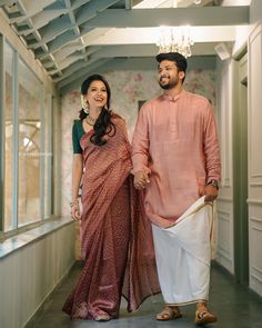 a man and woman walking down a hallway holding hands