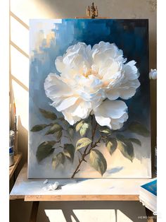 a large white flower sitting on top of a table next to a painting easel