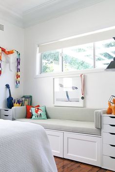 a bedroom with white walls and wooden flooring is pictured in this image, there are toys on the dressers