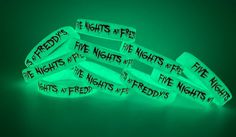 glow in the dark bracelets with words written on them, sitting against a green background