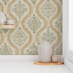 a white vase sitting on top of a counter next to a cup and saucer