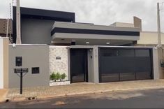 a grey house with black shutters on the front and side doors, in an urban area