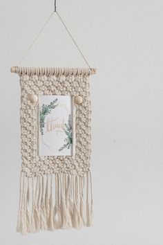 a white wall hanging with a thank you sign and some tassels on it